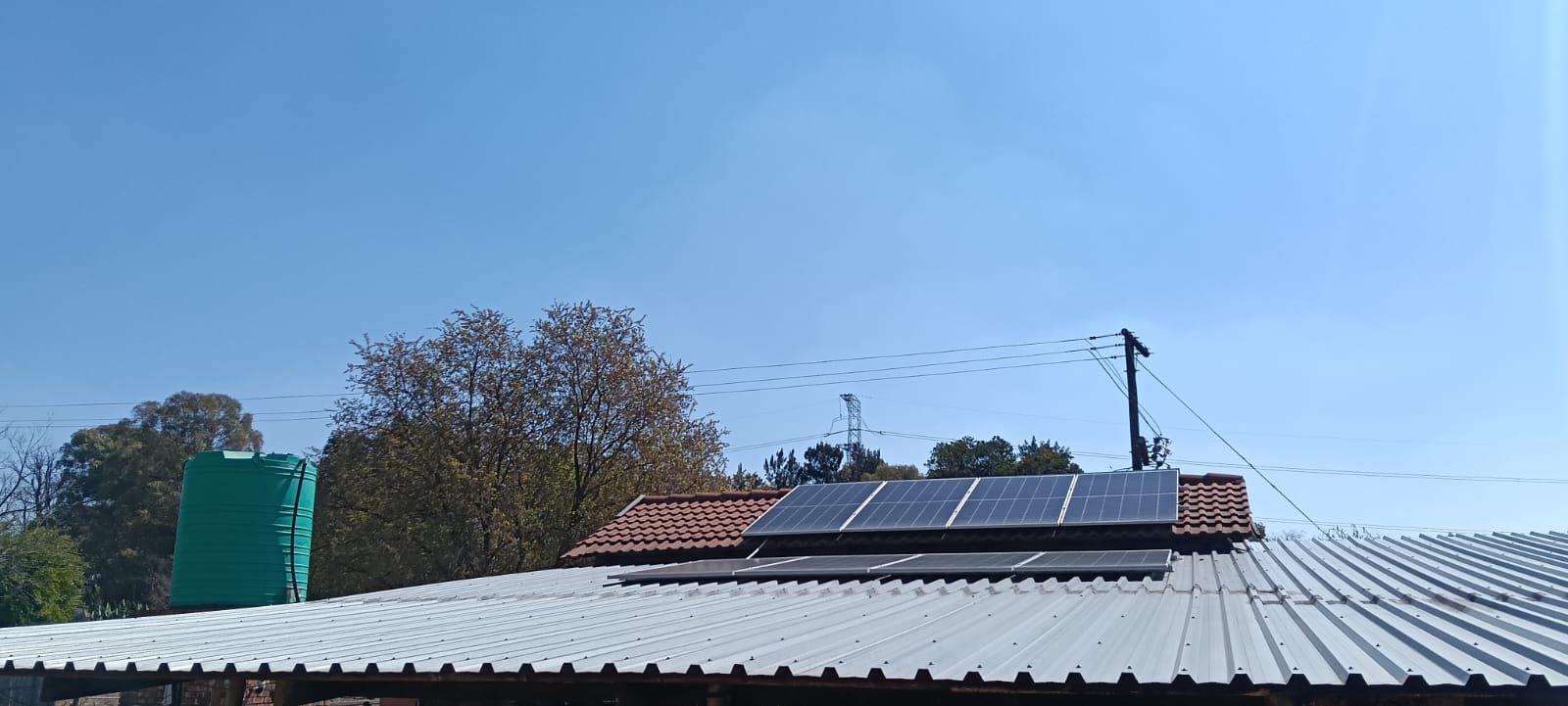 Solar panels on a metal roof with distant view of second array